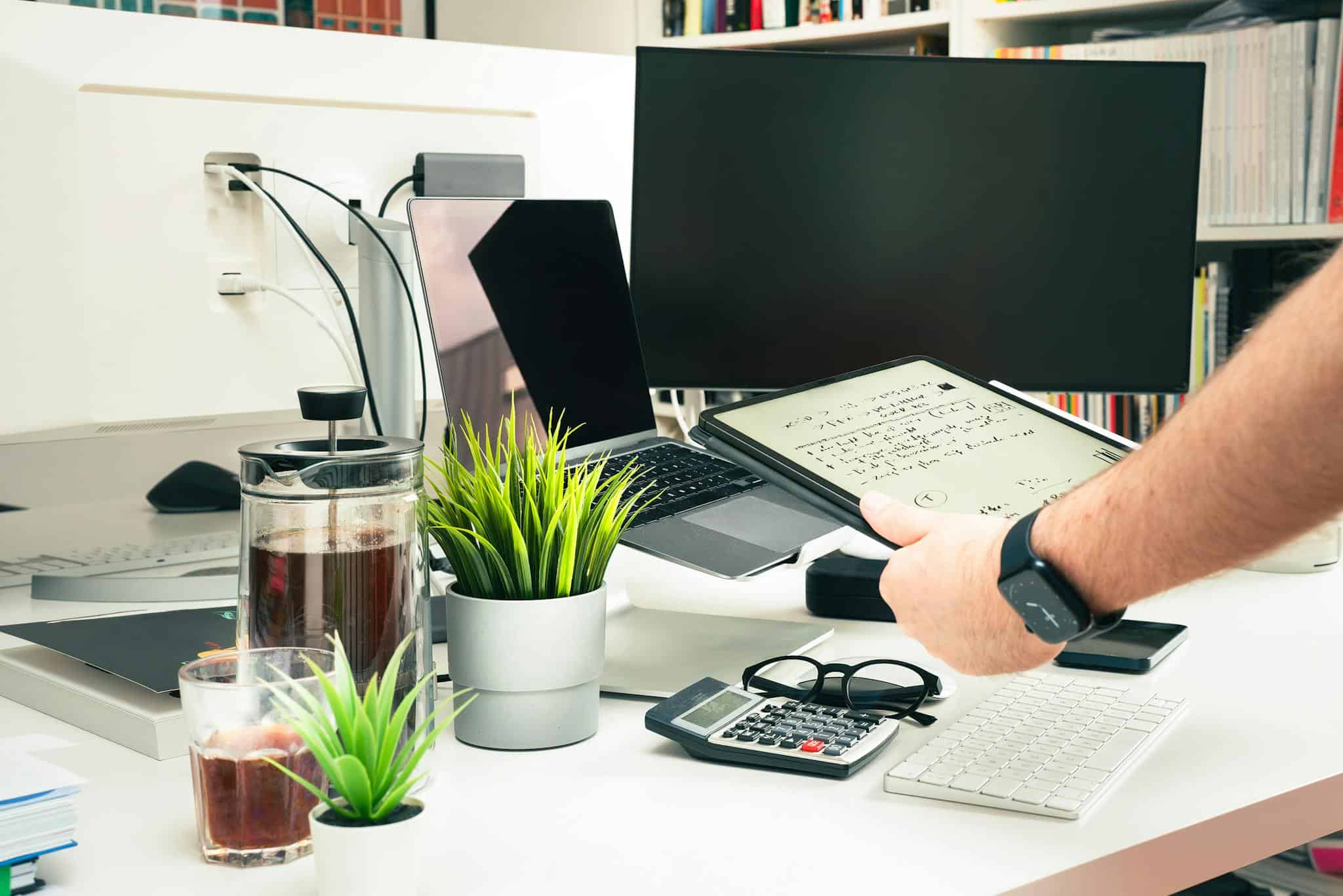 A contemporary office setup featuring technology and greenery on a desk.